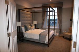 Castlecary House Hotel في كومبيرنولد: غرفة نوم مع سرير مظلة ونافذة