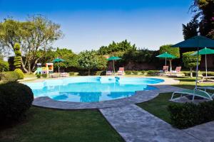 a swimming pool with chairs and umbrellas in a yard at Hotel San Francisco Leon in León