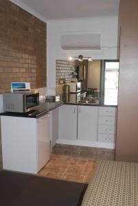 cocina con armarios blancos y microondas en Peppinella Motel, en Ballarat