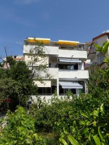 a white building with balconies and trees in front of it at Apartmani Villa Jasminka in Podgora