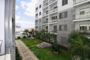 an apartment building with palm trees in the yard at Madeira Emotions Apartments by AnaLodges in Funchal