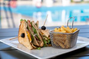 a sandwich and chips on a plate with a basket of chips at Coral Strand Smart Choice in Beau Vallon