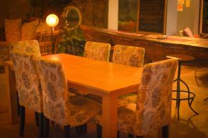 een houten tafel en stoelen in een kamer met een piano bij Boulevard Inn Mt Meru in Arusha