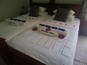 two beds with white sheets and flowers on them at Methira Villa in Aluthgama