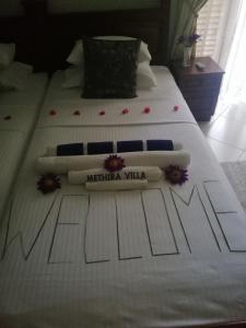 2 camas con sábanas blancas y un cartel de villa nacional. en Methira Villa, en Aluthgama