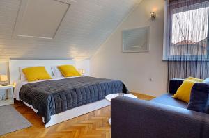 a bedroom with a bed with yellow pillows and a couch at Apartman studio SONAS 3 with free private parking in Karlovac