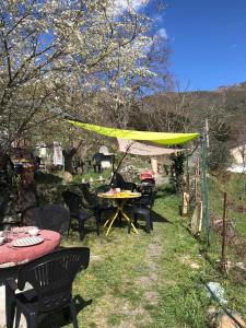 a patio with tables and chairs and a yellow canopy at camping l'agrottu au cœur de la corse restaurant creperie in Santa-Lucia-di-Mercurio