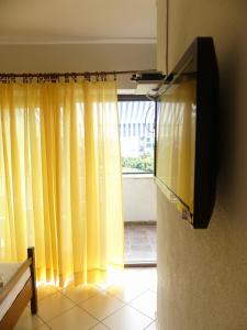 a room with yellow curtains and a tv on a wall at Apartmani Villa Jasminka in Podgora