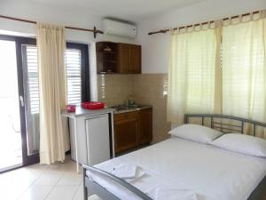a bedroom with a bed and a kitchen with a sink at Apartmani Villa Jasminka in Podgora