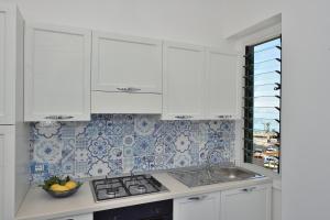 a kitchen with white cabinets and blue and white tiles at CASA FLAVIA in Maiori