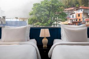 two beds with white pillows and a table with a lamp at My Boutique Hotel & Spa in Sa Pa