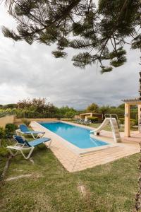 ein Pool mit zwei Liegestühlen daneben in der Unterkunft Quinta Vita - Vila Limao in Almancil