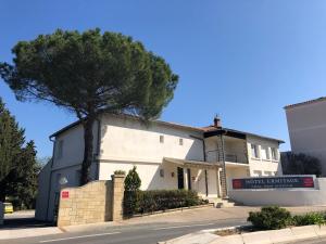 a white building with a tree in front of it at Hôtel Ermitage Avignon in Les Angles Gard
