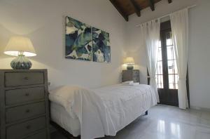 a bedroom with a bed and a dresser and a window at ALOJAMIENTO EN SEVILLA-TRIANA in Seville