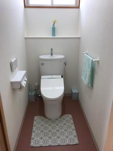 a white bathroom with a toilet and a rug at Megijima Island Guesthouse & cafe Megino in Takamatsu