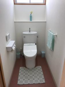 a white bathroom with a toilet and a rug at Megijima Island Guesthouse & cafe Megino in Takamatsu