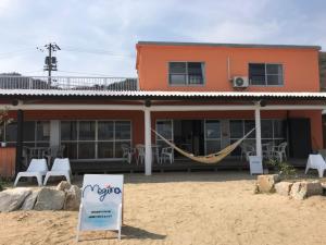 a building with a hammock in front of it at Megijima Island Guesthouse & cafe Megino in Takamatsu