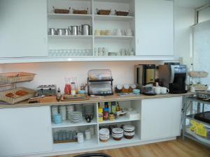 a kitchen with white cabinets and shelves with food at Hotel Colinette in Saint-Georges-de-Didonne