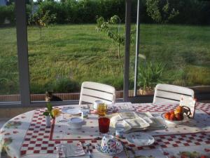 una mesa con un plato de comida y un gato sentado frente a una ventana en Chambre d'Hôte de la Belle Jardinière, en Chagny