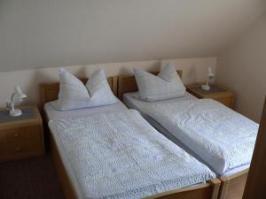 two beds with white pillows in a room at Hausnordlicht FEWO 3 in Dornum