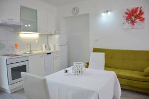 a white kitchen with a white table and a green couch at Downtown Sweet Studio in Novalja +16 photos