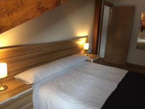 a large white bed in a bedroom with two lamps at Apartamentos La Solana in Potes