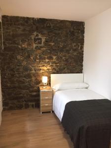 a bedroom with a bed and a stone wall at Apartamentos La Solana in Potes
