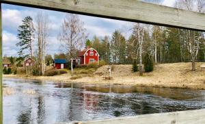 a red barn next to a river with a bridge at Cosy river house in Kvillsfors