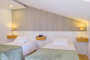 two beds in a room with white walls at Hotel Laranjeira in Viana do Castelo