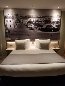 ein großes Bett mit einem schwarz-weißen Bild an der Wand in der Unterkunft NDS Prestige Guest House and Suites - by Rocha Prestige in Portimão