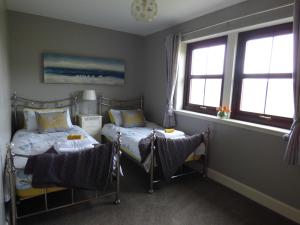 a bedroom with two beds and two windows at Ornum Self Catering Cottage in Eabost