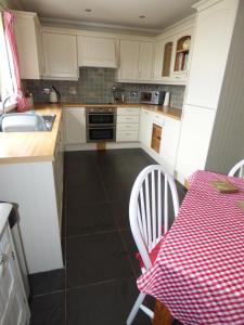 a kitchen with a table with a red and white checkered table cloth at Ornum Self Catering Cottage in Eabost