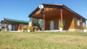 a log cabin with a porch and a grass field at Cabañas Aires de Campos in Colón