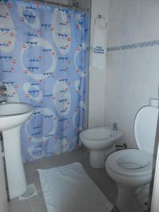 a bathroom with a sink and a toilet and a shower curtain at HOTEL 25 DE MAYO in Fray Bentos