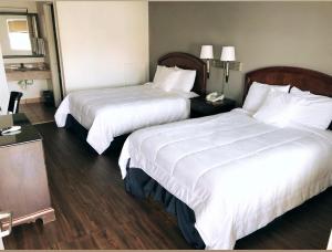 a hotel room with two beds with white sheets at Americas Best Value Inn-Princess Anne in Princess Anne