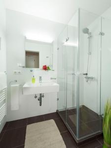 a white bathroom with a sink and a shower at BATU Apart Hotel in Munich