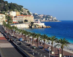 a busy street with palm trees and the ocean at Palais Hongran de Fiana in Nice