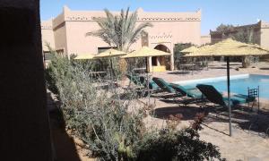 un resort con piscina, sedie e ombrelloni di Les Portes Du Desert a Merzouga