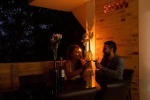 un hombre y una mujer sentados en una mesa con copas de vino en Eco Hotel El Columpio, en Salento