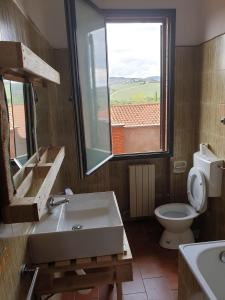 bagno con lavandino, servizi igienici e finestra di AZ.AGR.POGGIO REGINI a Castellina in Chianti