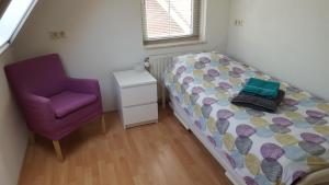 1 dormitorio con cama y silla morada en Augustinushof 13, en Vrouwenpolder