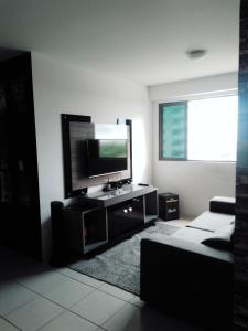 a living room with a flat screen tv and a couch at Apt alto padrão todo mobiliado e decorado em cond. Fechado in Maceió
