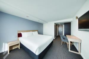 ein Hotelzimmer mit einem Bett und einem TV in der Unterkunft Central Studio Hotel Sydney in Sydney