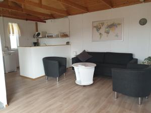 sala de estar con sofá, sillas y mesa en Við-Bót Riverside Cottage, en Egilsstadir