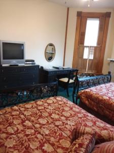 a bedroom with two beds and a desk with a television at Inn Port D'Vino in Dayton
