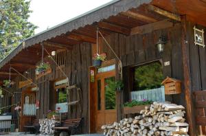 a log cabin with a porch and a bunch of logs at Hôtel Chalet Le Caribou in Les Saisies