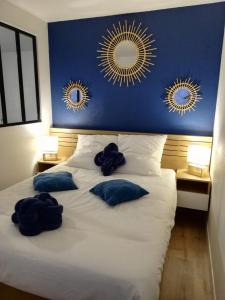 a bed with two blue pillows and two mirrors on the wall at Appartement Cosy proche Météo France et Airbus in Toulouse