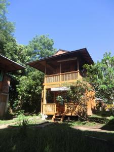 duży drewniany dom z balkonem i drzewami w obiekcie Bunaken Sea Garden Resort w mieście Bunaken