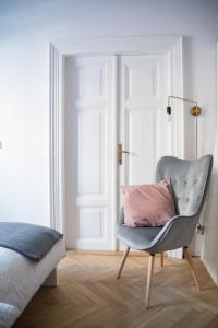 - une chaise avec un oreiller rose dans la chambre dans l'établissement LION apartments, à Cracovie