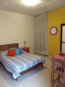 a bedroom with a bed with colorful pillows at Tu casa Oaxaca... in Oaxaca City